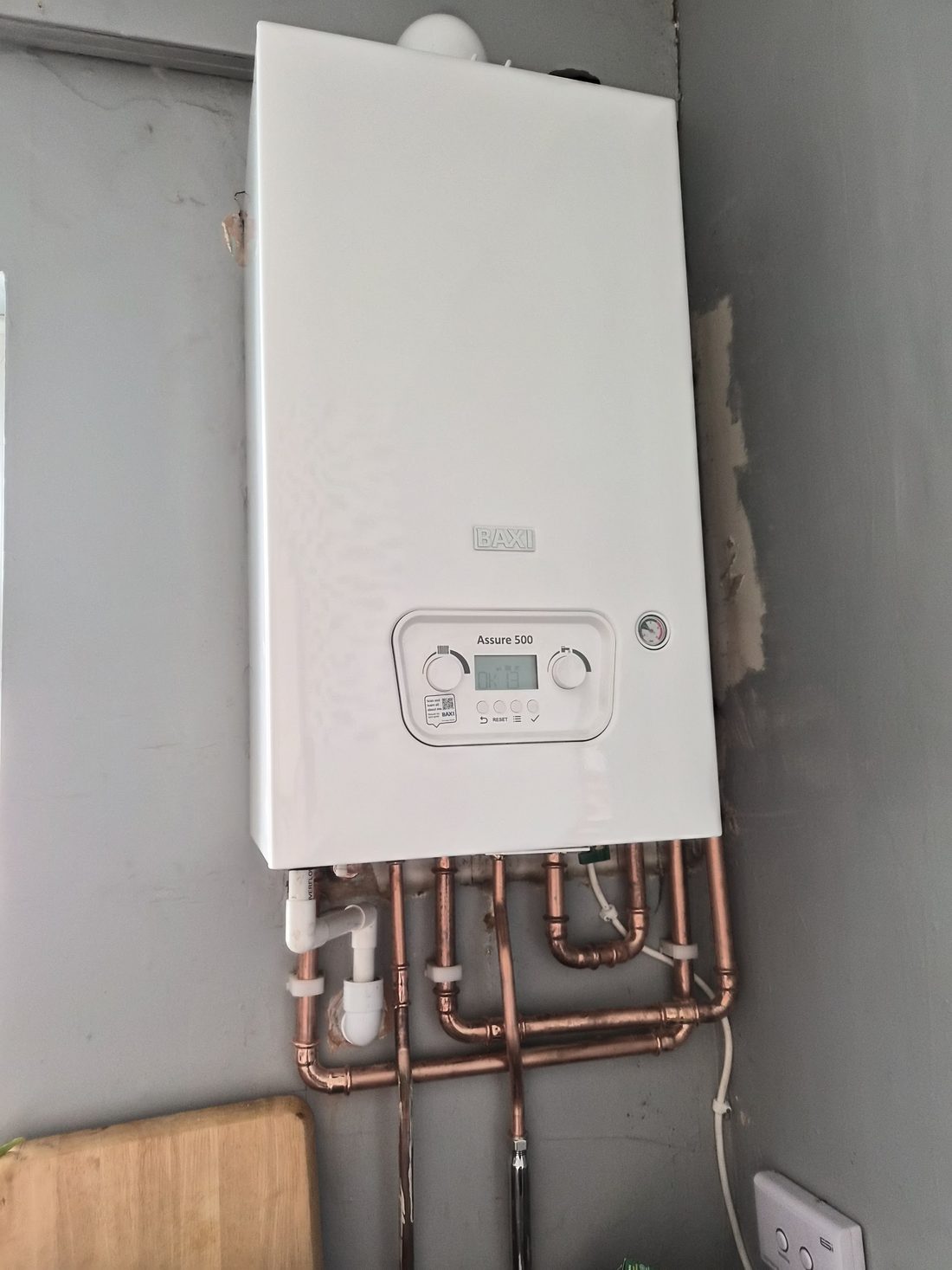 A boiler fitted in a utility space with its pipework underneath