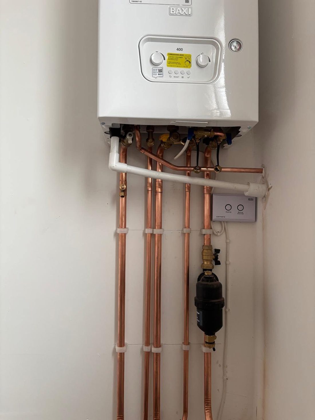 A wall-mounted combi boiler with neat copper pipework