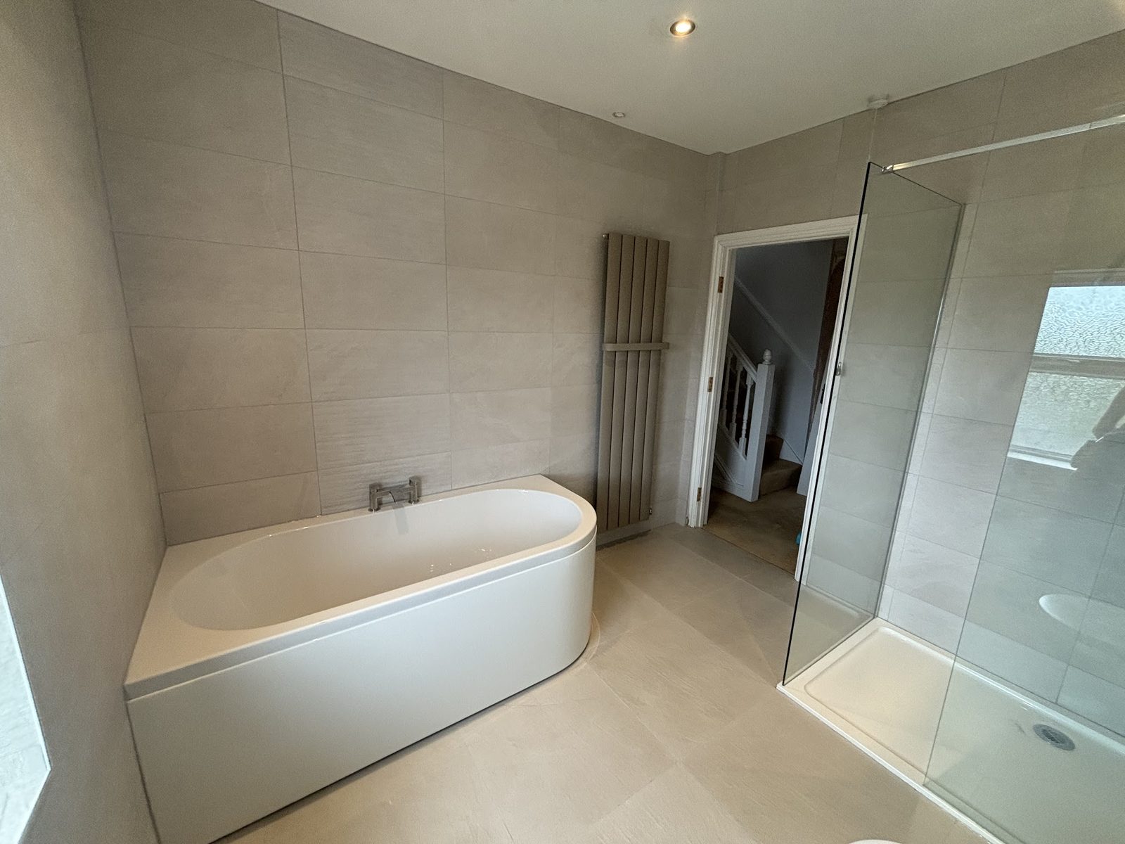 A bathroom with a freestanding bath, a glazed shower and a tall radiator